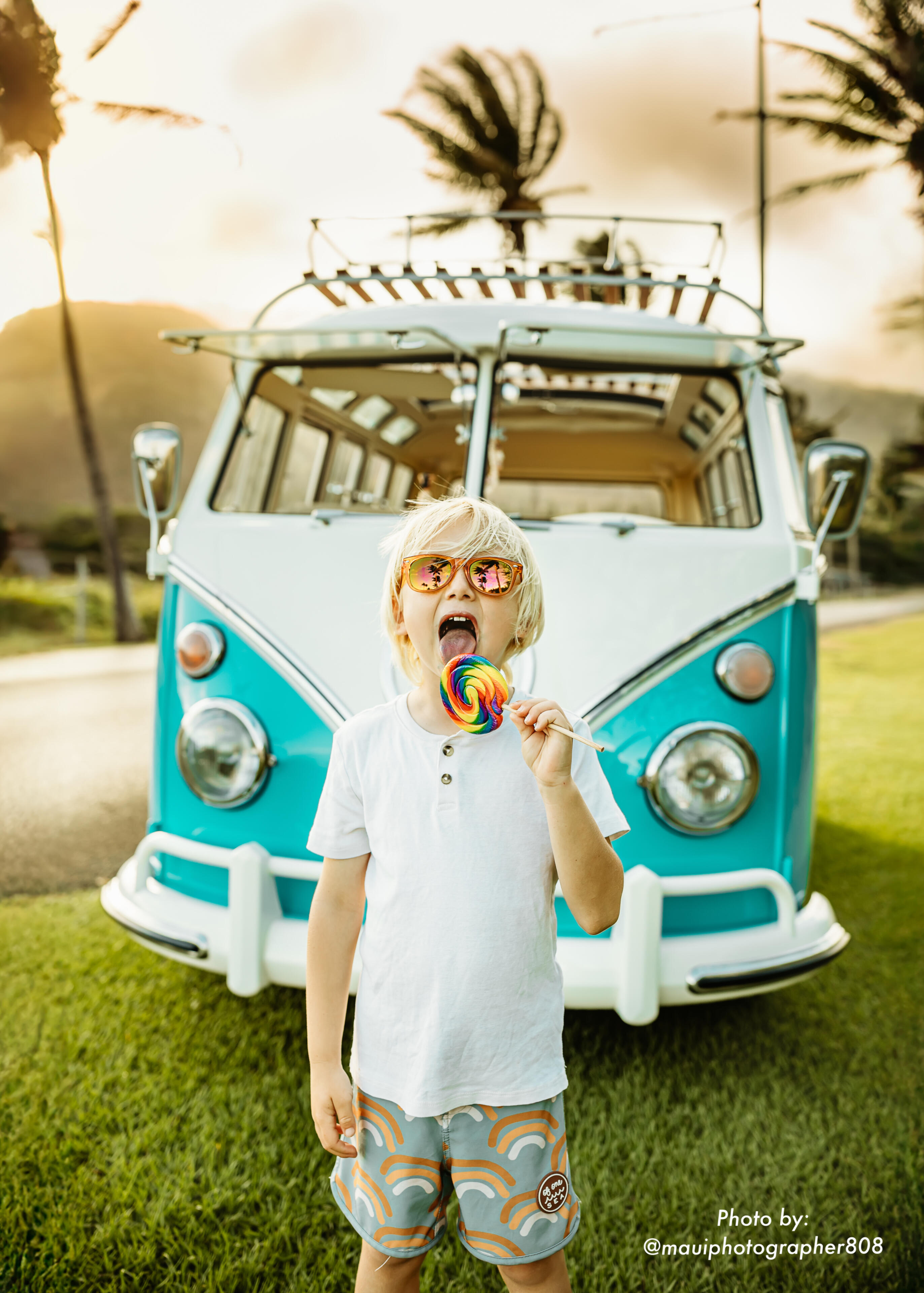 Child enjoying a lollipop in front of a vintage 1967 VW bus on Maui